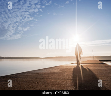 Ein Mann geht auf die Betonpfeiler im Sonnenlicht Stockfoto