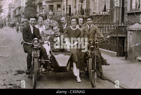 Eine Gruppe von Freunden und Familie sitzt auf einem Motorrad und Beiwagen Kombination in einer Straße in Fulham, London in den 1920er Jahren. Stockfoto