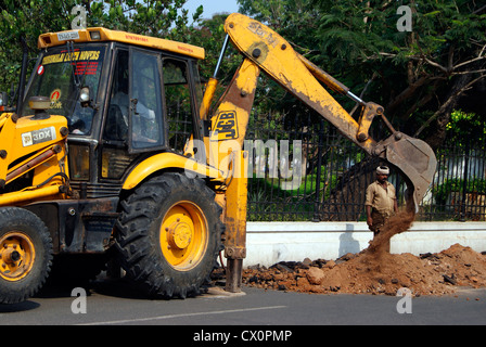 JCB Bagger Graben Erde von Tarred Straße in der Stadt Pondicherry in Indien für Wartung funktioniert Stockfoto