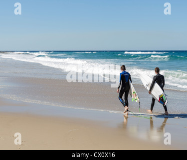 Zwei Surfer zu Fuß am Strand mit Surfbrettern am Sunshine Coast, Queensland, Australien Stockfoto