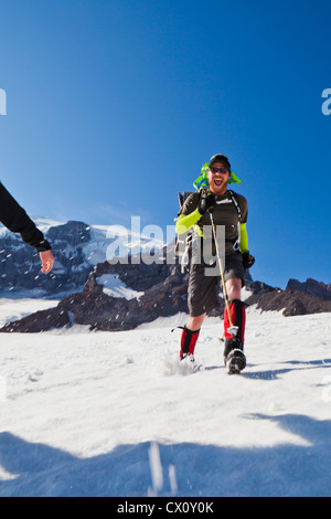 Ein junger Mann läuft das Schneefeld Muir auf Mount Rainier, Washington, USA. Stockfoto