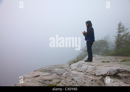 Mann auf einer Klippe im Regen und Nebel Stockfoto