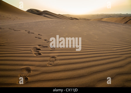 Fußspuren im Sand bei Sonnenaufgang in der Wüste Ramlat al-Sab'atayn, Jemen Stockfoto