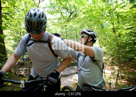 Mountainbiker, die Befestigung des Freundes Rucksack Stockfoto