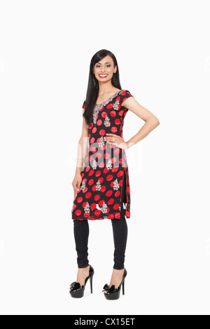 In voller Länge Portrait von indischen Frauen in traditionellen tragen stehend mit Hand auf Hüfte über grauen Hintergrund Stockfoto