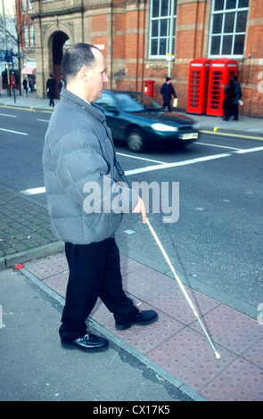 Blinder Mann mit einem langen Stock zugunsten der Straßenkreuzung, Leicester, UK. Stockfoto