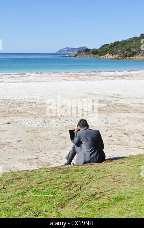 Business-Mann mit einem Laptop während der Suche über einen Strand, Albany, Western Australia Stockfoto
