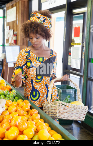 Afroamerikanische Frau im traditionellen Verschleiß für Früchte im Supermarkt einkaufen Stockfoto