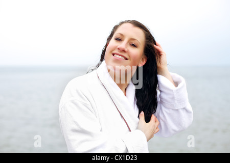 Frau, kämmen und trocknen Sie ihr Haar im Freien in einem windigen Strand Stockfoto