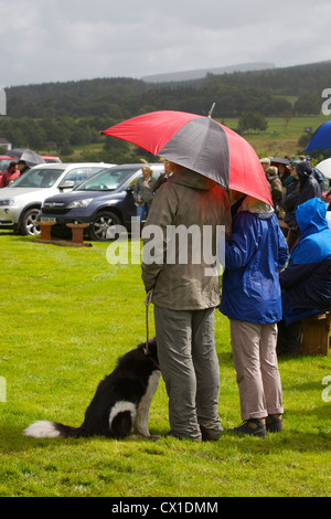 Hund, Mann und Frau bergende unter Dach am Threlkeld Show, Threlkeld, Keswick, Lake District, Cumbria, England, UK Stockfoto