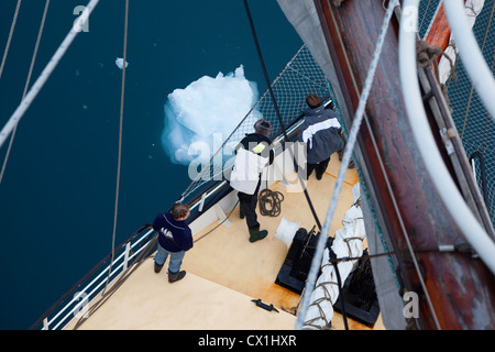 Touristen an Bord des Segelschiffes schmelzenden Eisberg im Meer in der Nähe von Svalbard, Spitzbergen, Norwegen schweben vorbei schauen Stockfoto