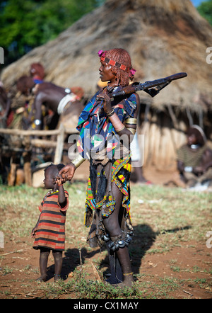 Hamar Frau hält eine AK47 auf der Suche nach ihrem Kind während einer Zeremonie Stier springen. Stockfoto