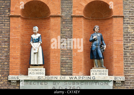 Statuen von ein Schulmädchen und jungen der Schule vor dem Gebäude, das der St John Wapping Primary School in London Stockfoto