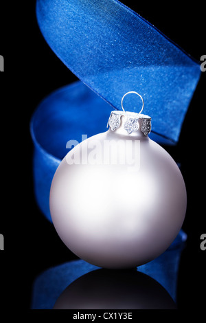 Matt Silber Christmas Ball vor einem blauen Band auf schwarzem Hintergrund Stockfoto