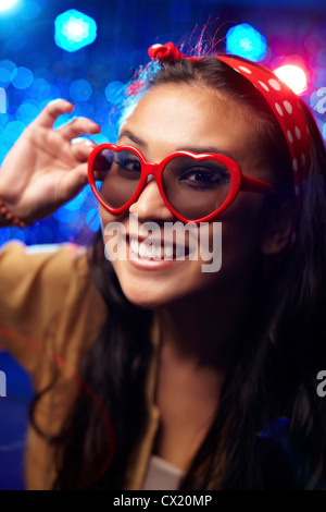 Lächelndes Mädchen mit herzförmigen Brille auf party Stockfoto