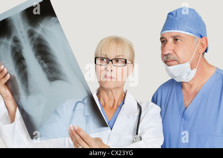 Ältere männliche Chirurg und Ärztin Blick auf x-ray grauer Hintergrund Stockfoto