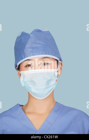 Nahaufnahme eines weiblichen Chirurgen tragen Gesichtsmaske über hellblauen Hintergrund Stockfoto