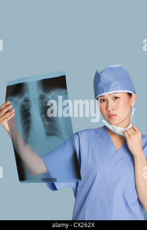 Porträt eines weiblichen Chirurgen Röntgen-Bericht über hellblauen Hintergrund halten Stockfoto