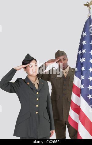Multi-ethnischen US-Offiziere salutieren amerikanische Flagge über grauer Hintergrund Stockfoto