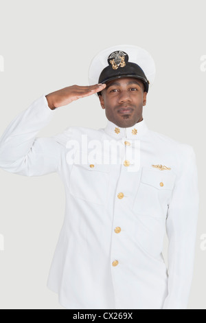 Porträt eines jungen African American US Navy Offiziers auf grauem Hintergrund grüßen Stockfoto