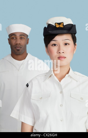 Porträt von schweren weiblichen US Navy Offizier im vorderen männlichen Seemann auf hellblauem Hintergrund Stockfoto