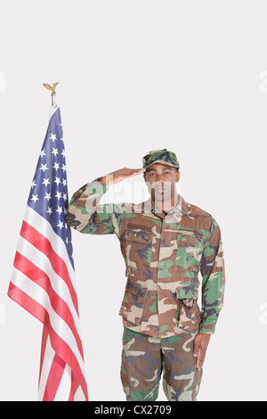 Porträt des US Marine Corps Soldaten salutieren amerikanische Flagge über dem grauen Hintergrund Stockfoto