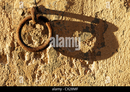 alte rostige Anlegestelle Ring auf Steinwand bei Sonnenuntergang mit langen Schatten Stockfoto