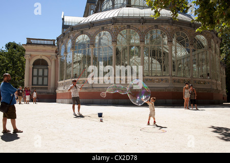 Ein Junge will platzen eine Seifenblase außerhalb der Palacio de Cristal im Retiro-Park, Madrid, Spanien. Stockfoto