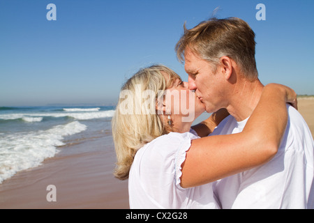liebevolle Mitte im Alter von paar küssen am Strand Stockfoto