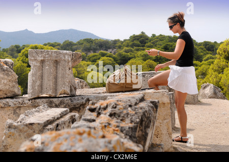 Ein Tourist gilt Sonnencreme auf einer Tour des Tempel des Aphaiatempels oder Afea auf der griechischen Insel Ägina Stockfoto