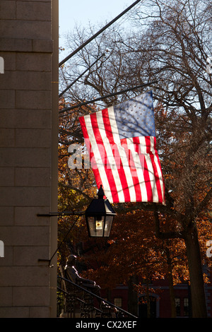 Flagge der USA über die John Harvard Statue in Harvard Yard, das alte Herz der Campus der Harvard Universität in Cambridge, MA. Stockfoto