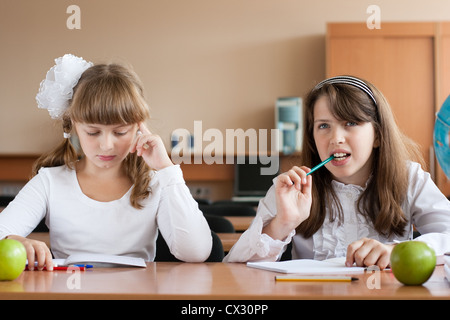 Zwei Mädchen sitzen auf der Schulbank während der Lektion Stockfoto