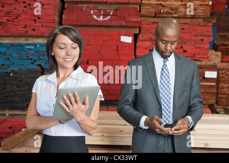 Multiethnische Geschäftskollegen mit Tablet-PC und Handy mit gestapelten Holzbohlen im Hintergrund Stockfoto