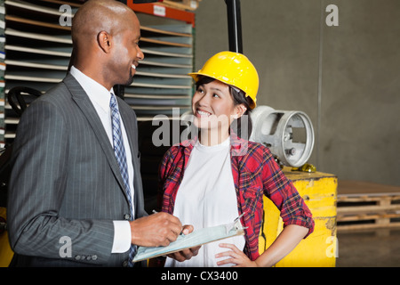 Industrielle Arbeitnehmerin männlichen Inspektor zu betrachten, da er in Zwischenablage schreibt Stockfoto