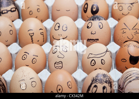 Lustige Gesichter auf bemalten auf braunen Eiern, angeordnet in Karton Stockfoto
