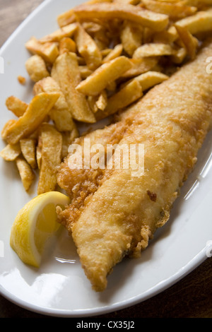 Weißen Teller battered Fish And Chips mit Zitronenscheibe auf Tisch Stockfoto