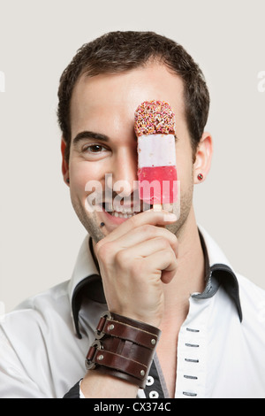 Close-up Portrait des jungen Mann, der Eisdiele vor grauem Hintergrund hält Stockfoto