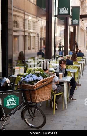 Kunden sitzen außerhalb der Whole Foods Market am Piccadilly Circus, London Stockfoto