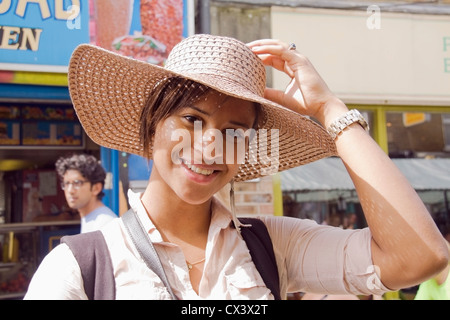 Eine junge Frau, die versucht, auf einen Sombrero-Hut in Broadway Market, London Fields, London, Großbritannien. Stockfoto