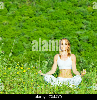 Foto schöne Frau tun Yoga-Übung im Freien, psychische Gesundheit, gesunde Lebensweise, süße junge Dame sitzt im Lotus pose Stockfoto