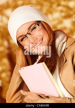 Foto von hübschen Studentin im herbstlichen Park und tragen Beige Ledermantel mit weißen Mütze, Closeup Portrait Teenager weiblich Stockfoto