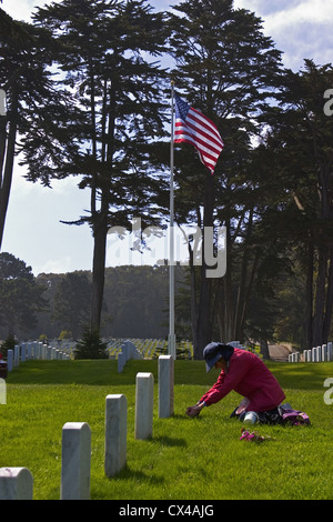 Eine Frau legt Blumen auf einen Servicemann Grab in San Francisco Presidio Militärfriedhof, Kalifornien, USA. Stockfoto