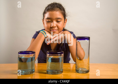 Ein Kind sieht bei identischen Gläser gefüllt mit der gleichen Menge Flüssigkeit Piagets flüssige Erhaltung Experiment nachweisen. Stockfoto