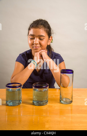 Ein Kind sieht bei identischen Gläser gefüllt mit der gleichen Menge Flüssigkeit Piagets flüssige Erhaltung Experiment nachweisen. Stockfoto