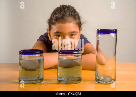 Ein Kind sieht bei identischen Gläser gefüllt mit der gleichen Menge Flüssigkeit Piagets flüssige Erhaltung Experiment nachweisen. Stockfoto