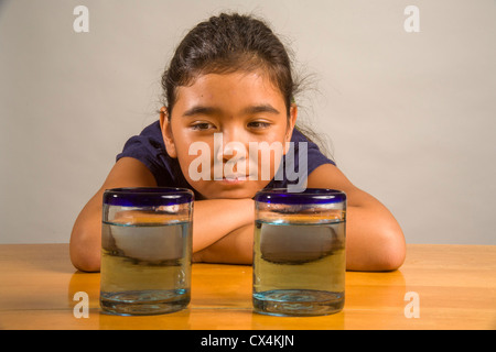 Ein Kind sieht bei identischen Gläser gefüllt mit der gleichen Menge Flüssigkeit Piagets flüssige Erhaltung Experiment nachweisen. Stockfoto