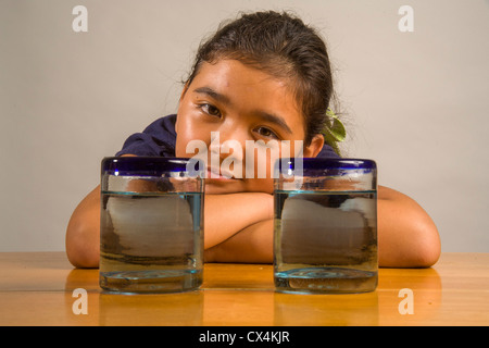 Ein Kind sieht bei identischen Gläser gefüllt mit der gleichen Menge Flüssigkeit Piagets flüssige Erhaltung Experiment nachweisen. Stockfoto