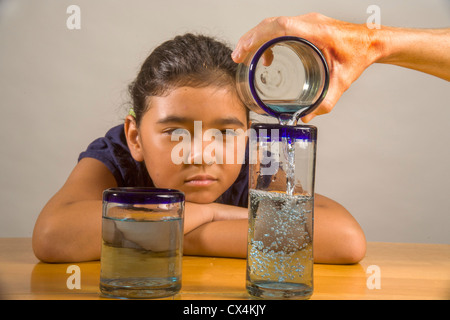 Ein Kind sieht bei identischen Gläser gefüllt mit der gleichen Menge Flüssigkeit Piagets flüssige Erhaltung Experiment nachweisen. Stockfoto