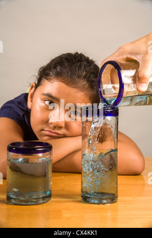 Ein Kind sieht bei identischen Gläser gefüllt mit der gleichen Menge Flüssigkeit Piagets flüssige Erhaltung Experiment nachweisen. Stockfoto