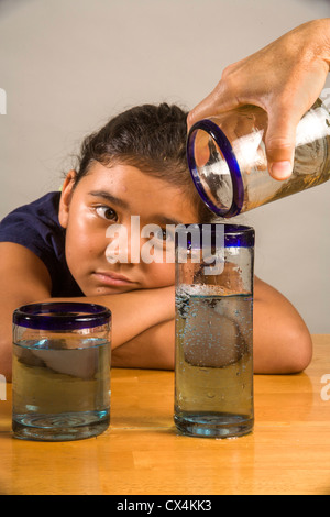 Ein Kind sieht bei identischen Gläser gefüllt mit der gleichen Menge Flüssigkeit Piagets flüssige Erhaltung Experiment nachweisen. Stockfoto